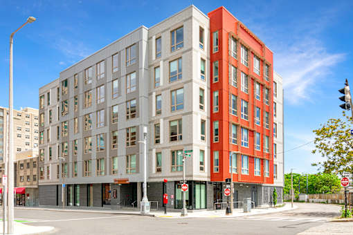A modern multi-story building with a red and grey facade at Pok Oi Residences, Boston, MA, Massachusetts, 2111
