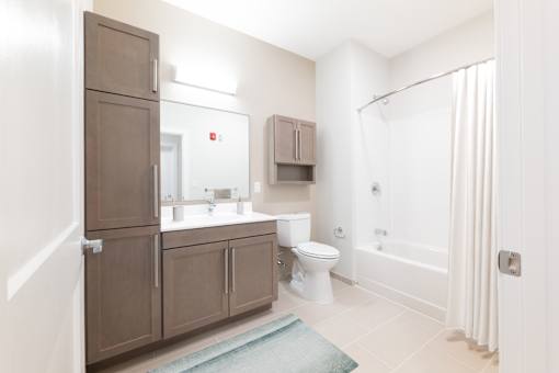 A bathroom with brown cabinets and a white toilet. at The Anne M. Lynch Homes at Old Colony, South Boston, Massachusetts