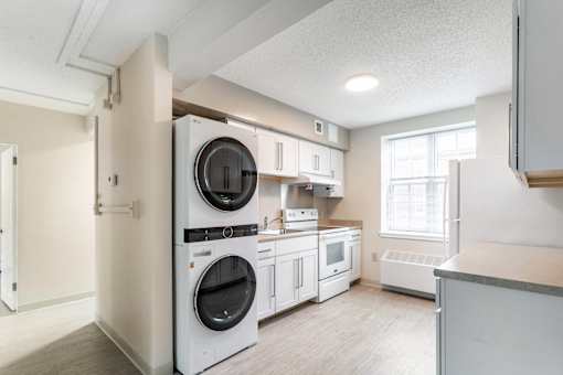 A white kitchen with a washer and dryer built in.