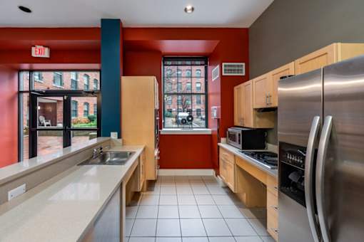 A kitchen with a red wall and a stainless steel refrigerator at The Cordovan at Haverhill Station, Haverhill, MA