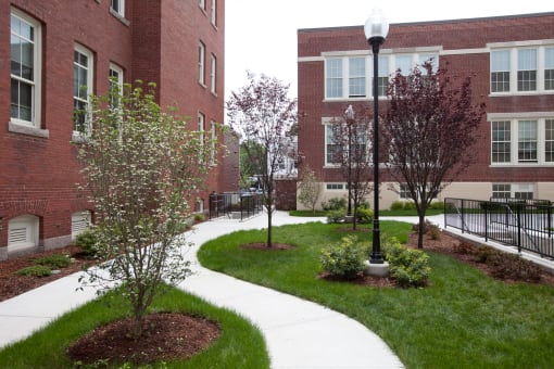 Exterior Of Building With Walkways And Tree's Sacred Heart Apartments.