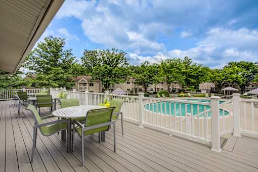 A wooden deck with a table and chairs overlooking a pool at Williamsburg Estates, Harrisburg, PA, 17112