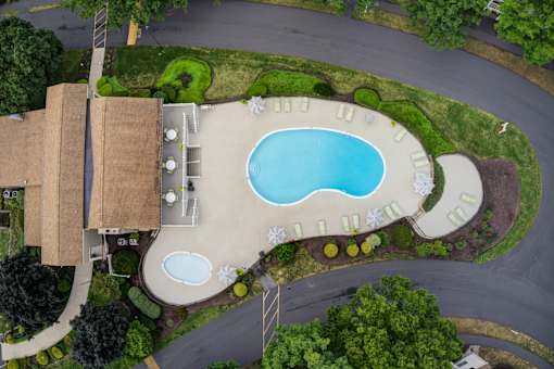 An aerial view of a swimming pool surrounded by a grassy area and trees at Williamsburg Estates, Harrisburg, PA, 17112
