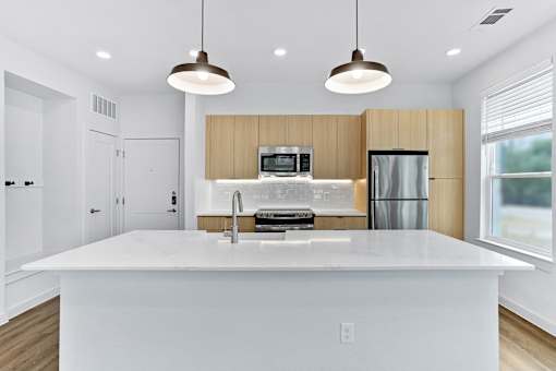 A modern kitchen with a large island and pendant lights.