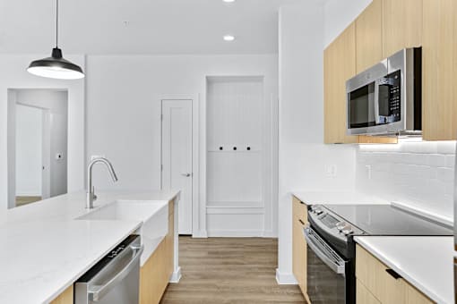 A modern kitchen with a white countertop and stainless steel appliances.