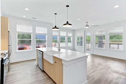 A modern kitchen with a large island and pendant lights.