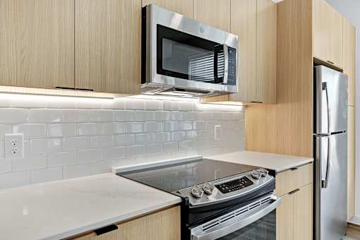 A modern kitchen with a stove, microwave, and refrigerator.