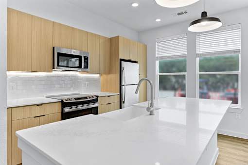 A modern kitchen with a white countertop and wooden cabinets.