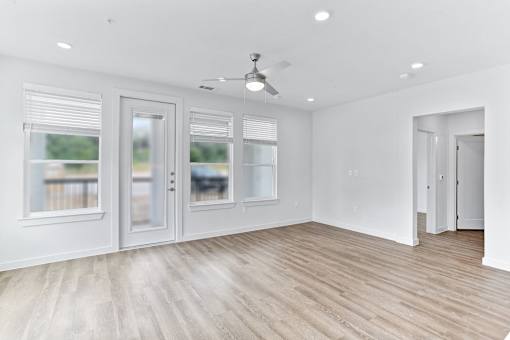 A room with a ceiling fan and sliding glass doors.