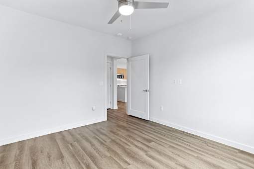 A room with a ceiling fan and wooden flooring.