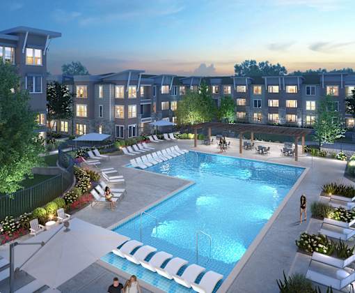 A swimming pool surrounded by lounge chairs and umbrellas in front of apartment buildings.