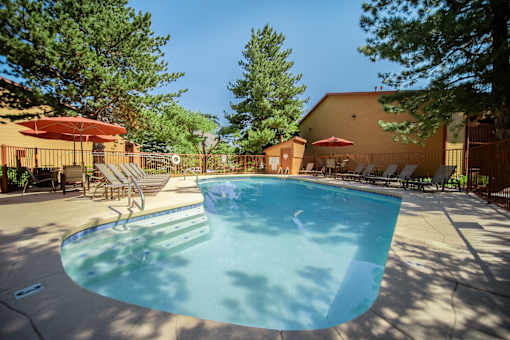 A swimming pool surrounded by trees and chairs.