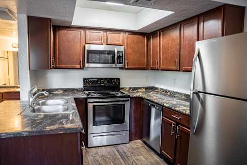 A kitchen with a stainless steel refrigerator, microwave, oven, and sink.