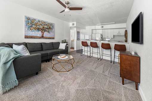 A living room with a grey couch, a coffee table, and a painting on the wall.