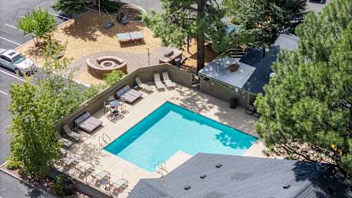 A swimming pool surrounded by a patio and trees.