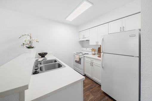 A kitchen with white appliances and cabinets.