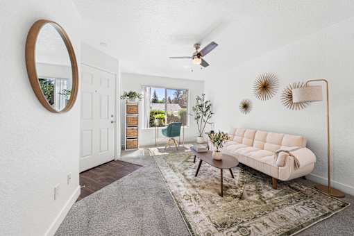A living room with a white couch, a rug, and a mirror on the wall.