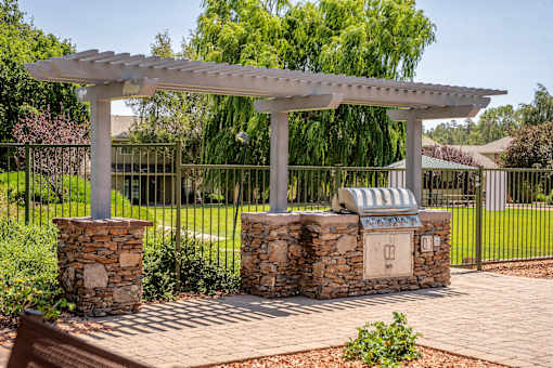 A white pergola is supported by two stone pillars.