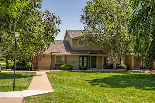 A house with a brown roof and a green lawn in front.