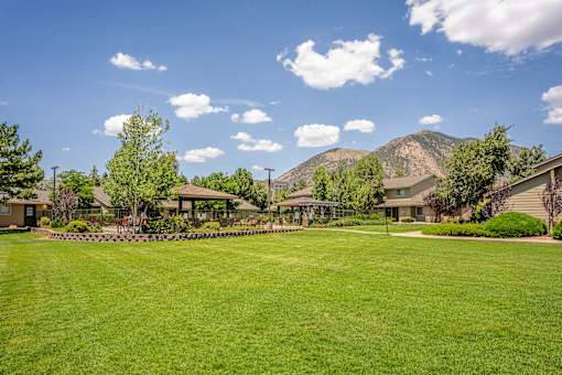 A large grassy field with a mountain in the background and apartments on the right side.