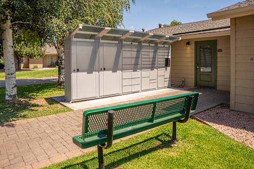 A green bench is in front of a storage shed.