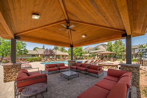 A patio with a table and chairs under a wooden roof.