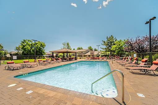 A large swimming pool surrounded by lounge chairs and trees.