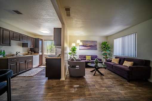 A living room with a purple couch and a painting on the wall.