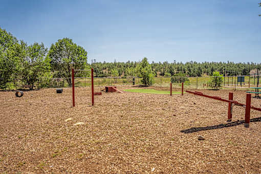 A dog park with red posts and a fence.