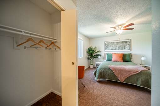 A bedroom with a bed, pillows, a ceiling fan, and a window.