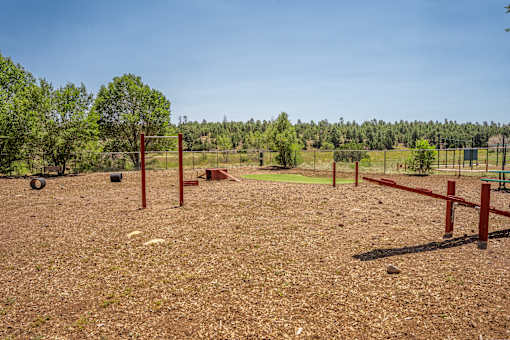 A dog park with red posts and a fence.