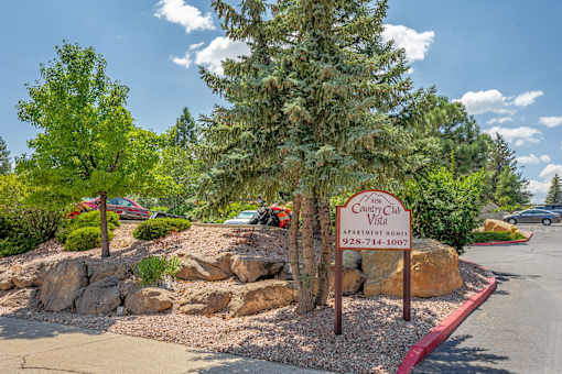 A sign for Country Club Apartments is in front of a landscaped area.