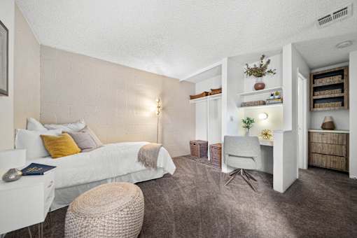A bedroom with a white bed and a grey chair.