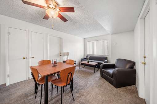 A room with a table, chairs, and a fan.