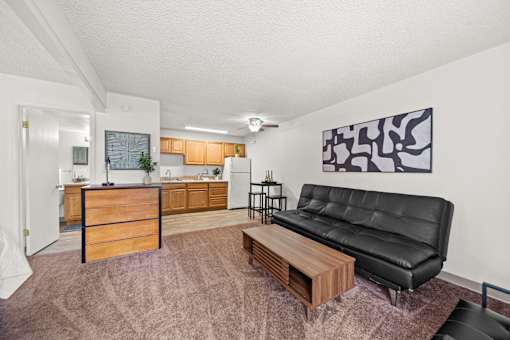 A living room with a black leather couch and a wooden coffee table.