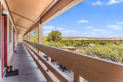 A long wooden balcony with and a view and trees in the distance.