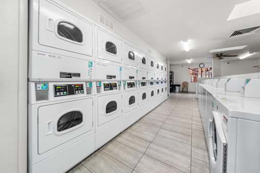 A row of white dryers and washing machinesin a laundromat.