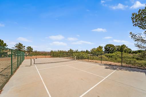A pickle ball court surrounded by a green fence.