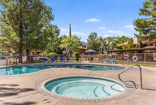 A swimming pool surrounded by trees and chairs.