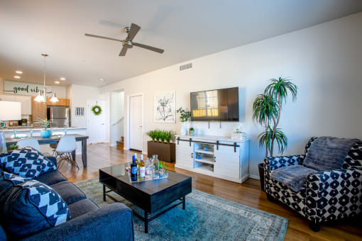 a living room with a couch coffee table and chairs and a kitchen in the background