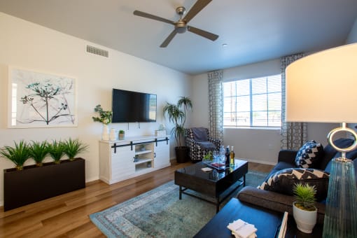 a living room with a ceiling fan and a tv on the wall