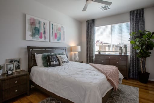 a bedroom with a large window and a ceiling fan