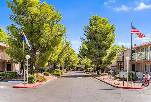 A street view of a residential area with houses on both sides and trees lining the road.