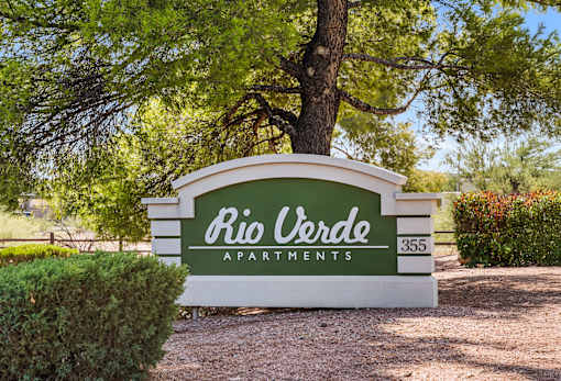 A sign for Rio Verde Apartments is displayed in front of a tree.