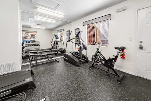 A fitness center with a treadmill, stationary bike, and weights.