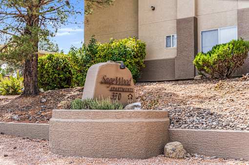 A sign that says Sagewood Apartments 370 is in front of a building.