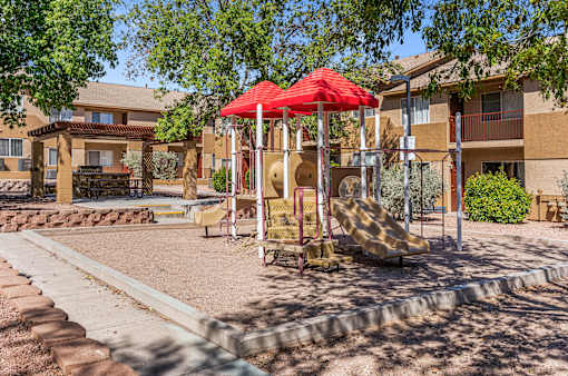 A playground with a red umbrella and a slide.