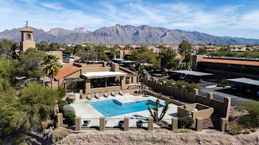 A pool surrounded by a fence and cacti with a mountain in the background.