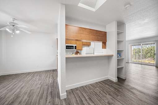 A room with a ceiling fan and a kitchenette.