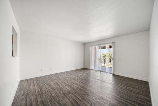 A room with wooden flooring and a window with blinds.